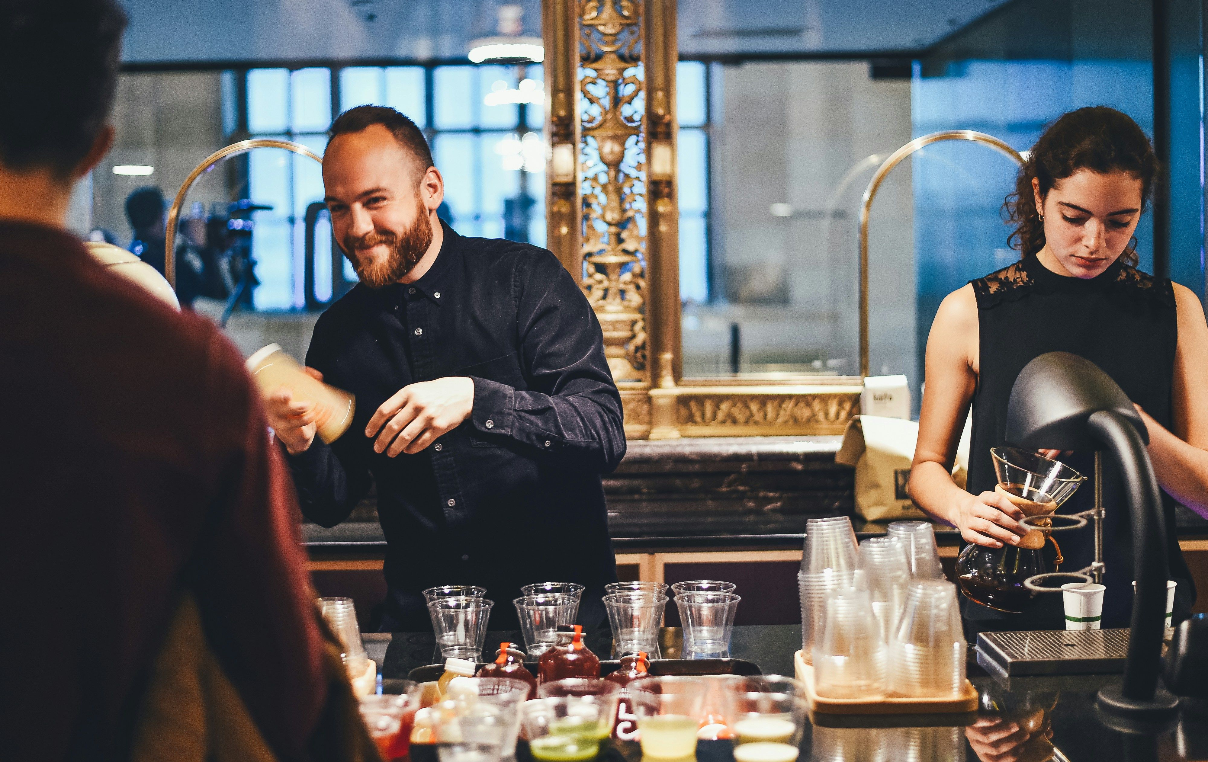 Two team members preparing drinks behind a bar counter